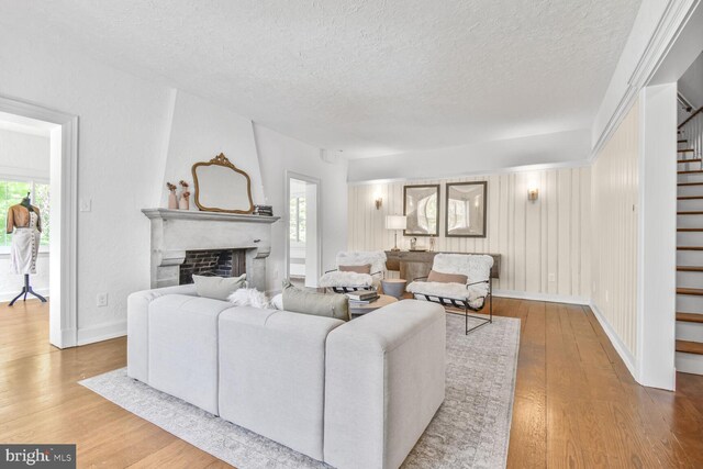 6911 Wells Pkwy, University Park, MD 20782 - living room featuring stairs, a textured ceiling, wood finished floors, a fireplace, and healthy amount of natural light