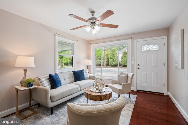 living area featuring baseboards, dark wood finished floors, and ceiling fan
