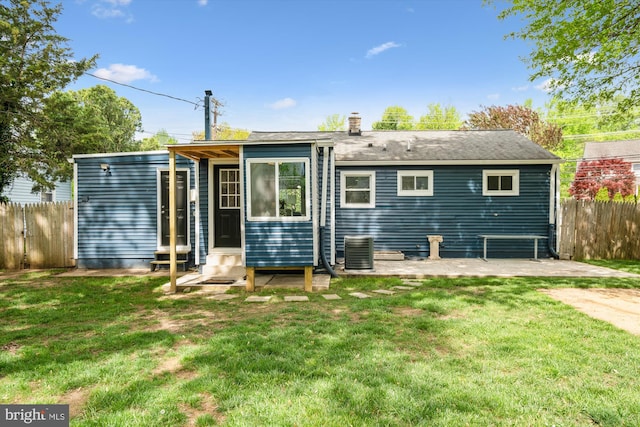 back of property featuring a chimney, a lawn, central AC, fence, and entry steps