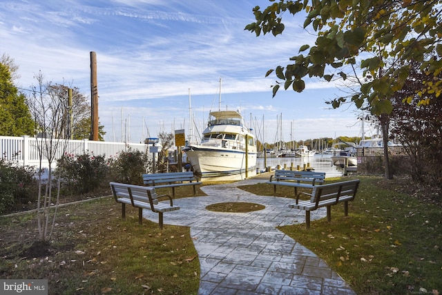 surrounding community with fence, a boat dock, and boat lift