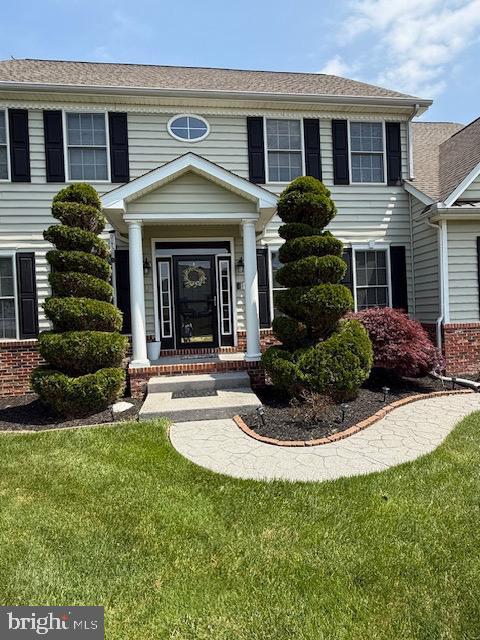 view of exterior entry with a yard and brick siding