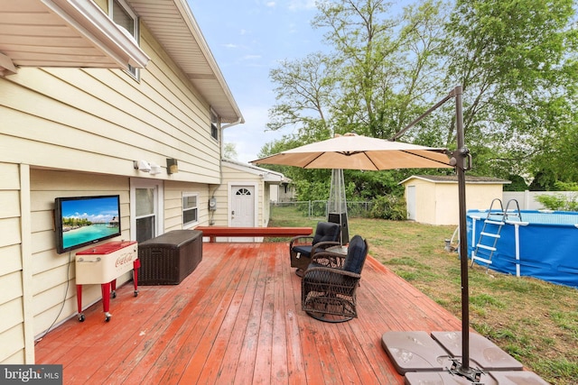 deck with an outdoor pool, a storage unit, and an outbuilding