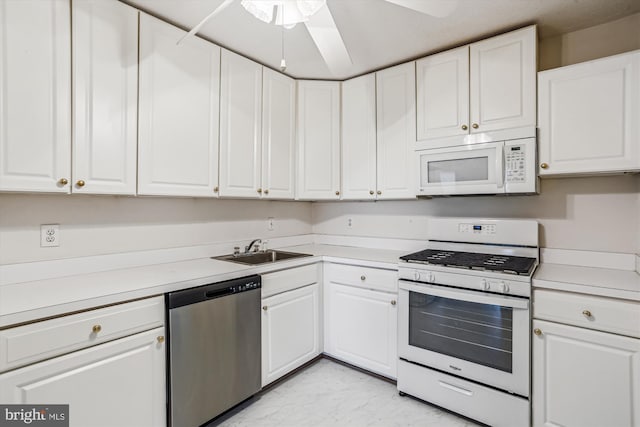 kitchen with white appliances, ceiling fan, light countertops, white cabinetry, and a sink