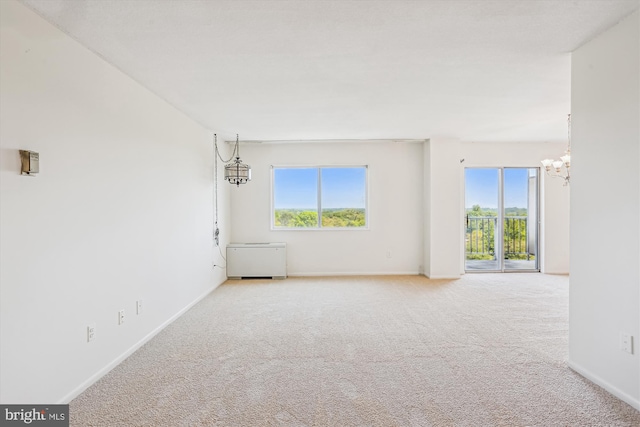 unfurnished room featuring carpet flooring, a notable chandelier, and a wealth of natural light