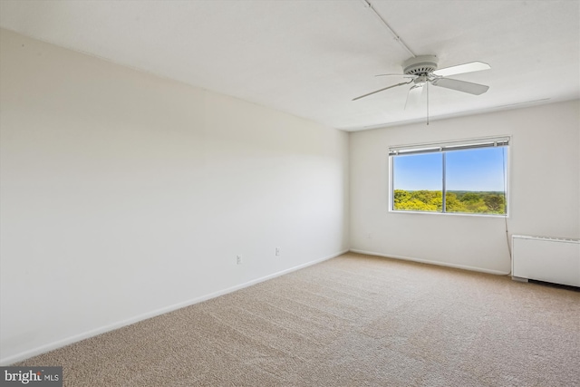 spare room featuring carpet floors, baseboards, ceiling fan, and radiator heating unit