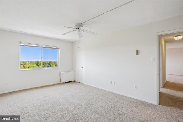 spare room with light colored carpet, baseboards, and ceiling fan
