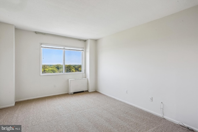empty room featuring baseboards, carpet flooring, and radiator