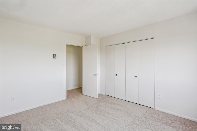 unfurnished bedroom with carpet floors, baseboards, and a closet