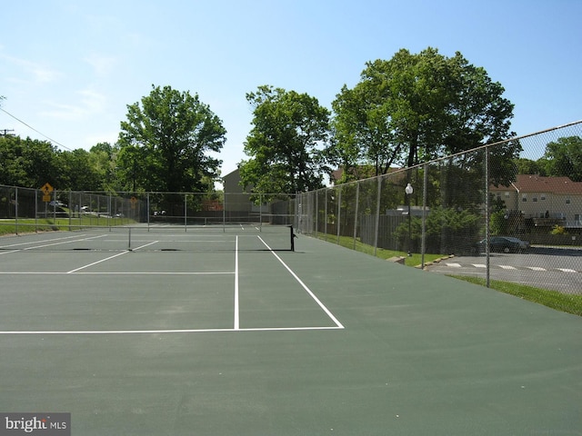 view of tennis court featuring community basketball court and fence