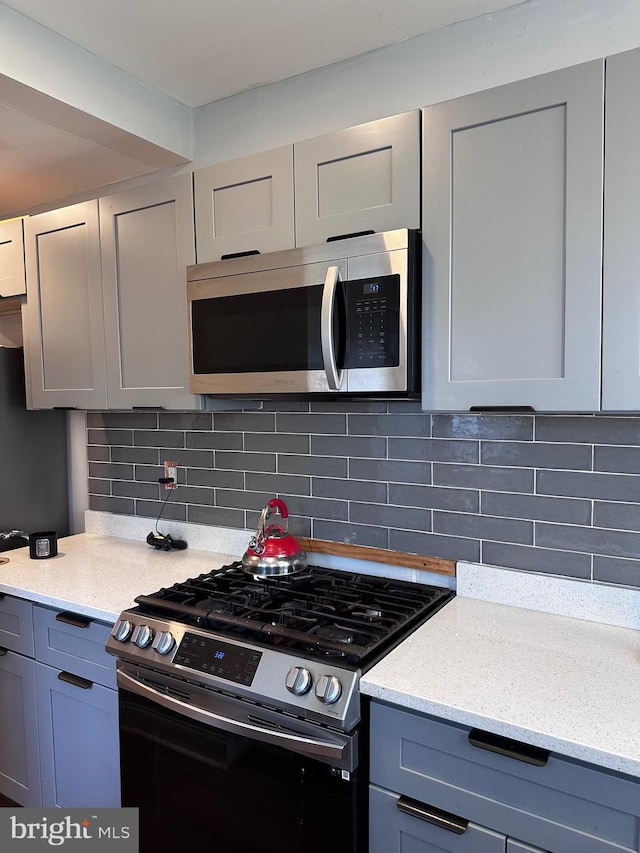 919 Edgemore Rd, Philadelphia, PA 19151 - kitchen featuring stainless steel appliances, gray cabinetry, light stone countertops, and backsplash
