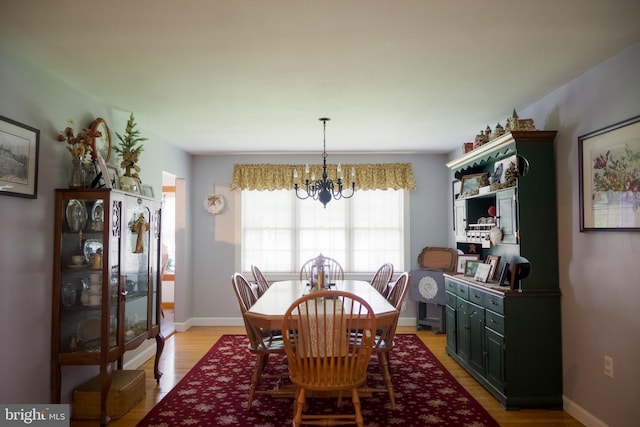 dining room with light wood-style floors, baseboards, and a notable chandelier