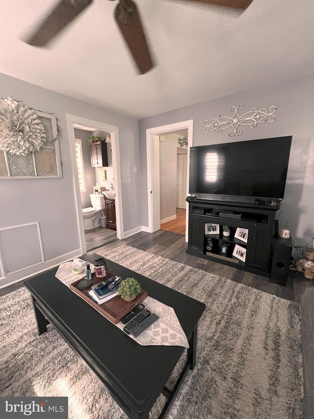 living room with baseboards, ceiling fan, and wood finished floors