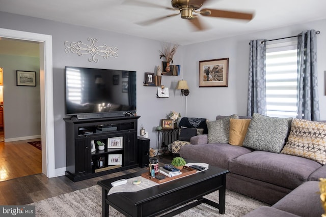 living area with baseboards, a ceiling fan, and wood finished floors