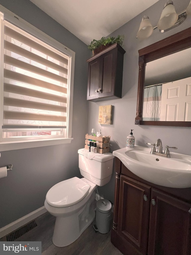 full bath featuring vanity, toilet, wood finished floors, and visible vents