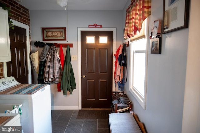 mudroom with dark tile patterned floors, baseboards, and separate washer and dryer