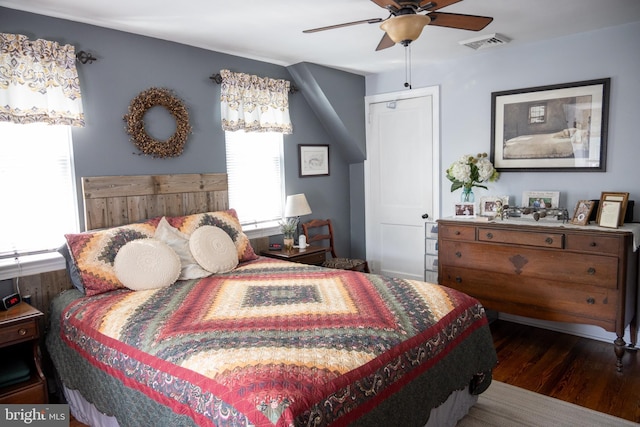 bedroom featuring a ceiling fan, visible vents, and wood finished floors