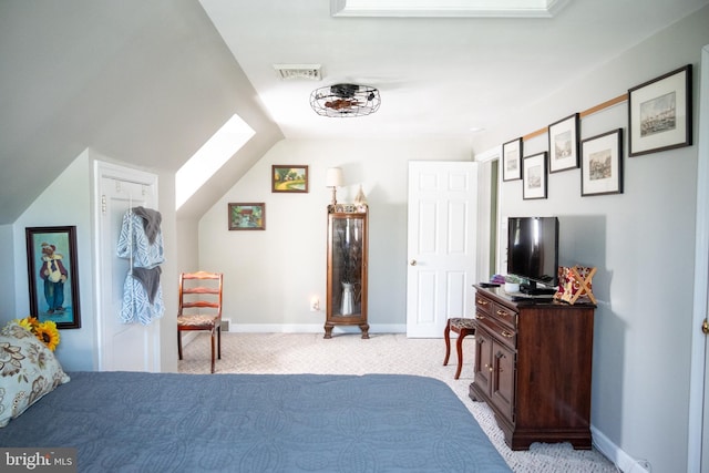 bedroom with baseboards, light colored carpet, visible vents, and vaulted ceiling with skylight