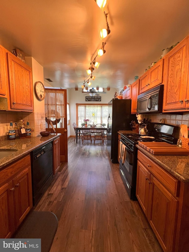 kitchen with decorative backsplash, dark wood-style flooring, brown cabinets, and black appliances