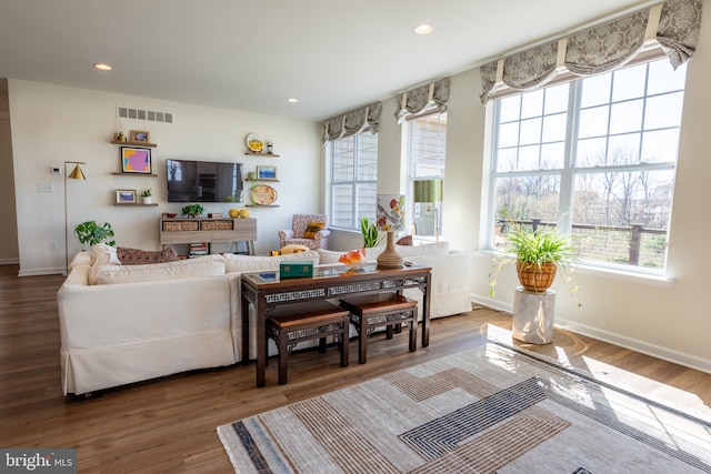 living area featuring baseboards, visible vents, plenty of natural light, and wood finished floors