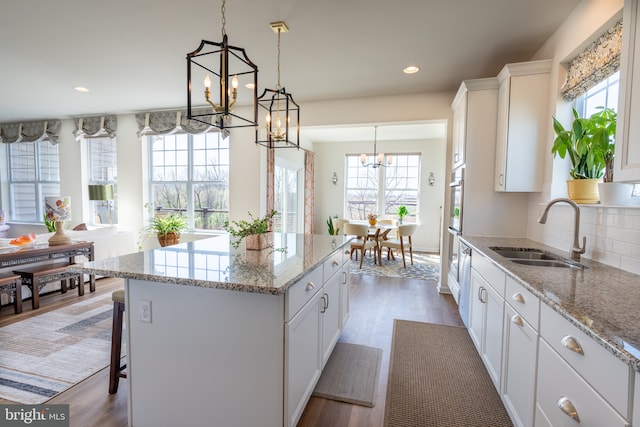 kitchen with an inviting chandelier, a sink, a kitchen island, and a wealth of natural light