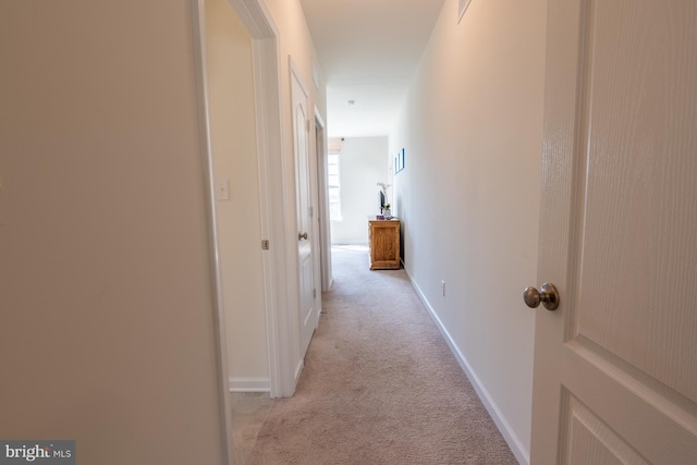 hallway featuring light colored carpet, baseboards, and visible vents