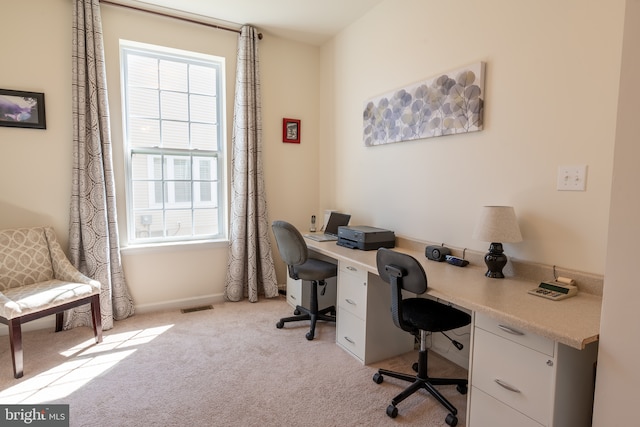 office with light colored carpet, baseboards, visible vents, and built in desk