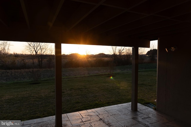 patio terrace at dusk featuring a lawn