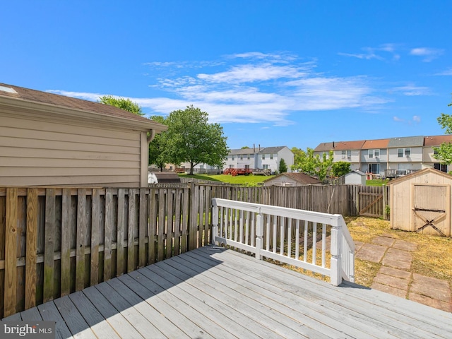 wooden terrace featuring a residential view, a storage shed, a fenced backyard, and an outdoor structure