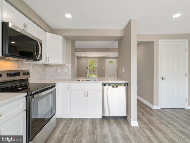 kitchen with appliances with stainless steel finishes, a sink, light wood-style floors, light countertops, and recessed lighting