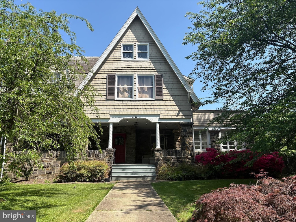 view of front of property featuring a porch, a front lawn, and stone siding