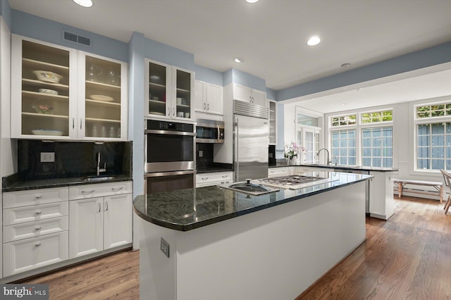 2720 35th Pl NW, Washington, DC 20007 - kitchen with stainless steel appliances, a sink, white cabinets, a center island, and glass insert cabinets
