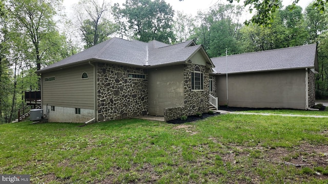 1982 Whyte Ln, Spring Grove, PA 17362 - back of property with stone siding, cooling unit, a lawn, view of wooded area, and roof with shingles