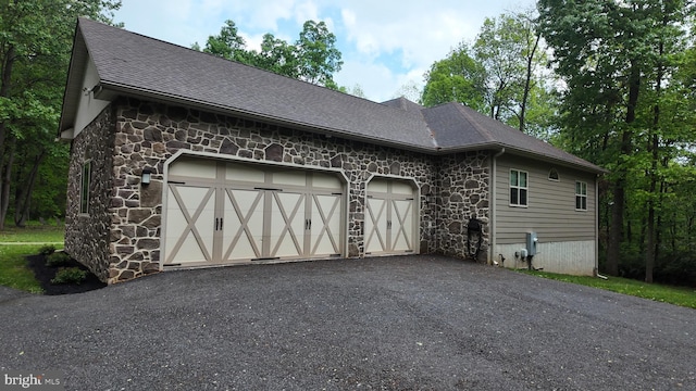 1982 Whyte Ln, Spring Grove, PA 17362 - view of property exterior featuring stone siding, a garage, a shingled roof, and asphalt driveway