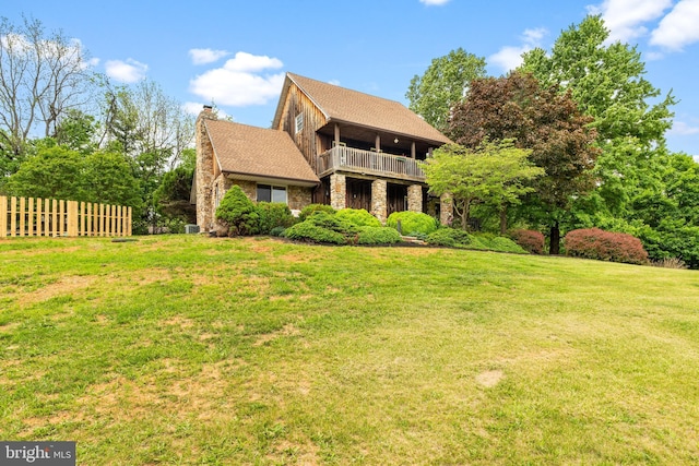 view of front of home featuring a balcony, a chimney, and stone siding