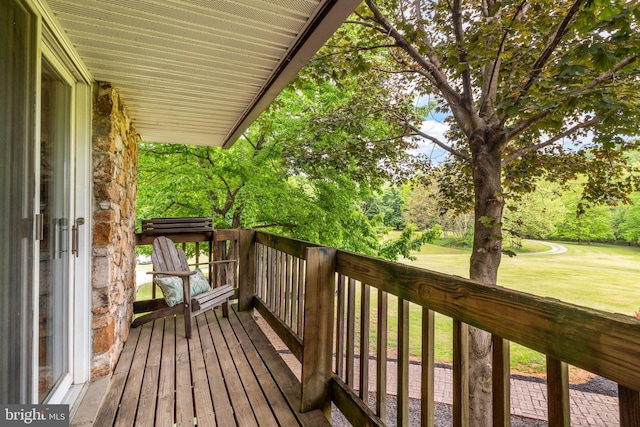 wooden terrace with a lawn and view of wooded area