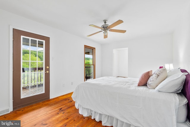 bedroom with access to outside, multiple windows, wood-type flooring, and baseboards
