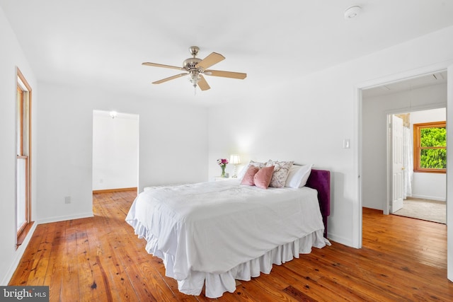 bedroom with attic access, light wood finished floors, baseboards, and a ceiling fan