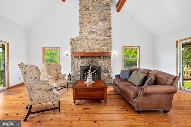 living room featuring high vaulted ceiling, wood-type flooring, beamed ceiling, plenty of natural light, and a stone fireplace
