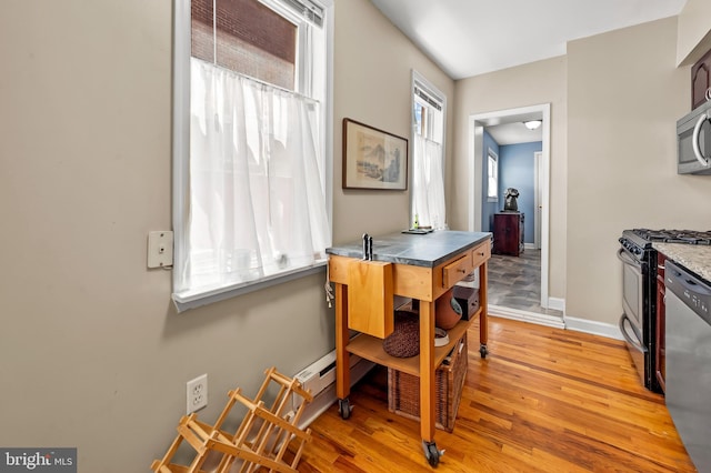 kitchen featuring baseboards, appliances with stainless steel finishes, and light wood-style floors