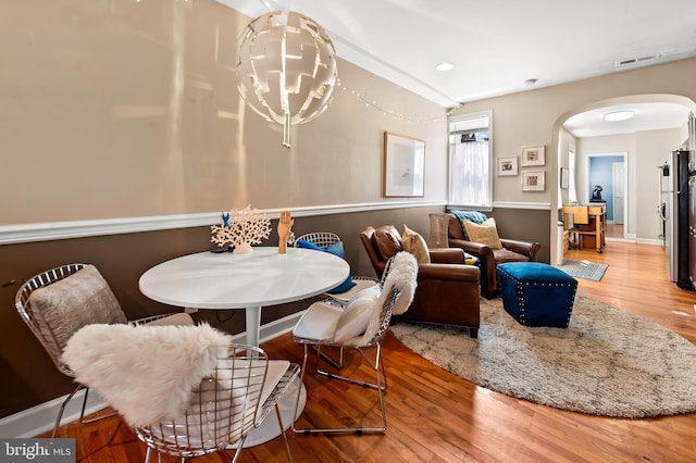 dining room with arched walkways, baseboards, wood finished floors, and visible vents