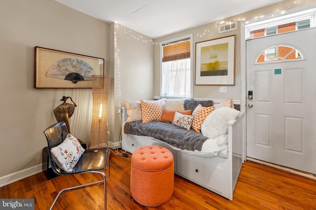 living area featuring baseboards, wood finished floors, and visible vents