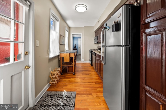 kitchen with light wood-style floors, baseboards, and stainless steel appliances
