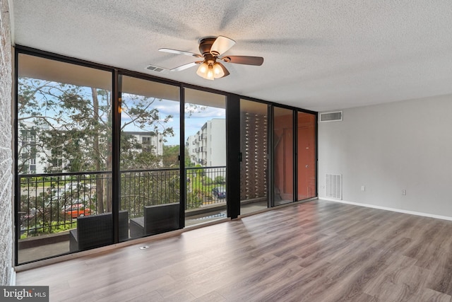 16 S Van Dorn St Unit 406, Alexandria, VA 22304 - empty room featuring a wall of windows, a textured ceiling, ceiling fan, wood finished floors, and healthy amount of natural light