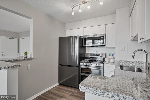 16 S Van Dorn St Unit 406, Alexandria, VA 22304 - kitchen with stainless steel appliances, a sink, light stone countertops, white cabinetry, and a textured ceiling