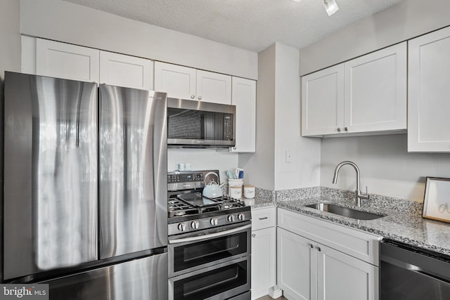 16 S Van Dorn St Unit 406, Alexandria, VA 22304 - kitchen featuring stainless steel appliances, a sink, white cabinets, a textured ceiling, and light stone counters