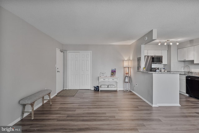 16 S Van Dorn St Unit 406, Alexandria, VA 22304 - kitchen with black dishwasher, stainless steel microwave, white cabinetry, wood finished floors, and light stone counters