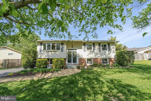 bi-level home featuring fence and a front lawn