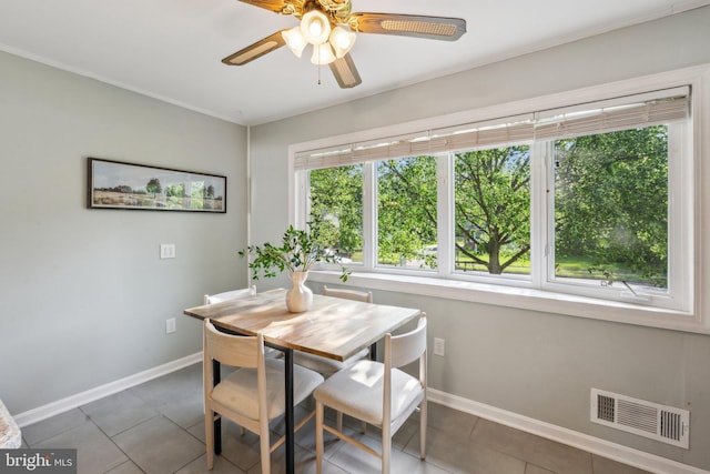 tiled dining space with crown molding, baseboards, a ceiling fan, and visible vents