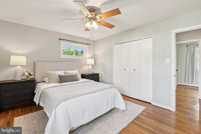 bedroom with a ceiling fan, baseboards, wood finished floors, and a closet