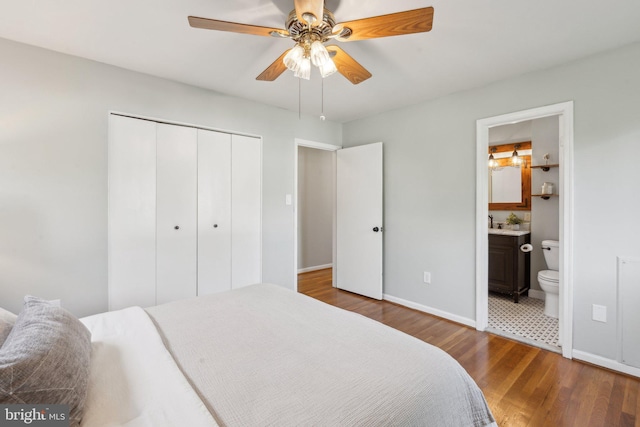 bedroom featuring a ceiling fan, baseboards, a closet, dark wood-style floors, and ensuite bathroom